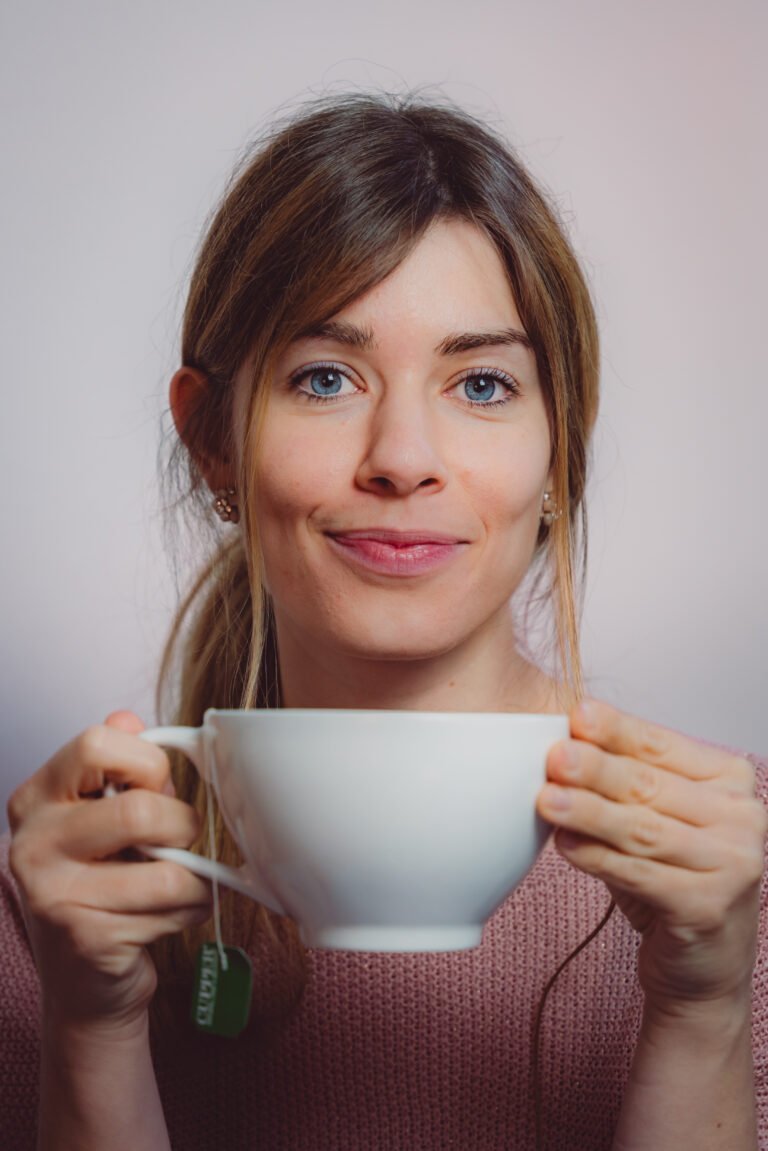 Rebecca Janko Copywriterin aus Dresden schaut mit einer Tasse Tee in der Hand in die Kamera