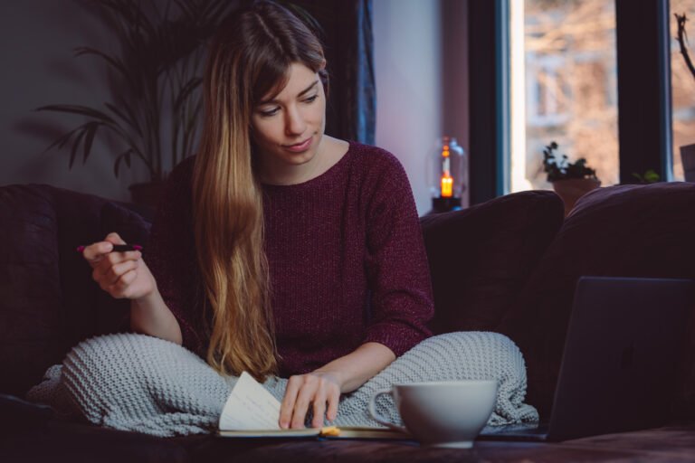 Rebecca Janko Copywriting in Dresden und Heilpraktikerin sitzt auf dem Sofa mit einem Notizbuch und einem Stift in der Hand und sammelt Ideen für Texte